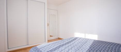 A bedroom with a bed, a wardrobe, a door, and a ceiling light.