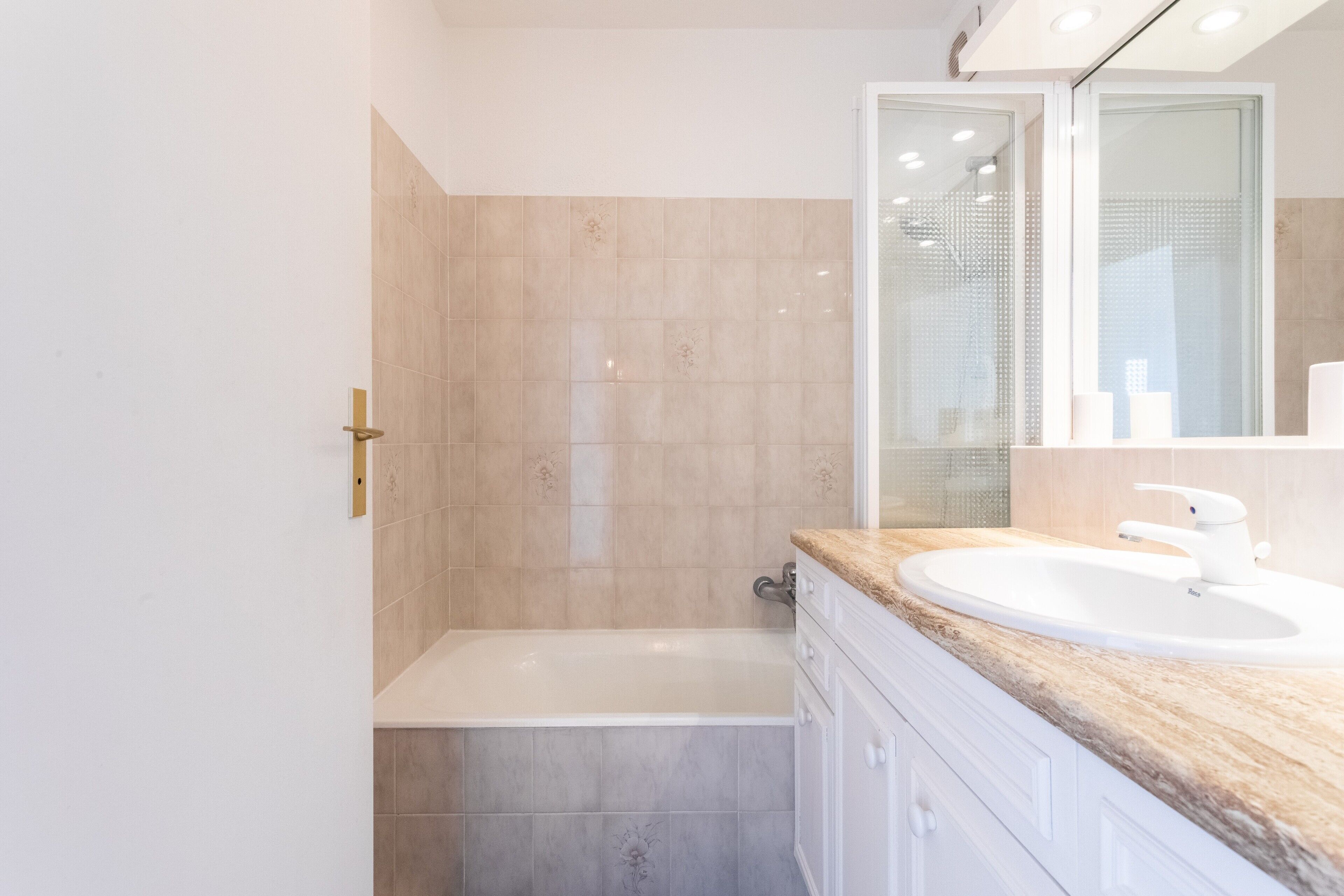 A bathroom with a bathtub, a sink, and a mirror.