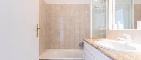 A bathroom with a bathtub, a sink, and a mirror.