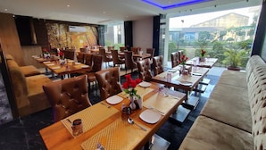 Un ristorante con diversi tavoli, sedie in pelle e vista sull'esterno.