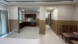 Una camera d'albergo con un letto, un tavolo da pranzo e sedie. Si nota anche una zona cucina sullo sfondo.