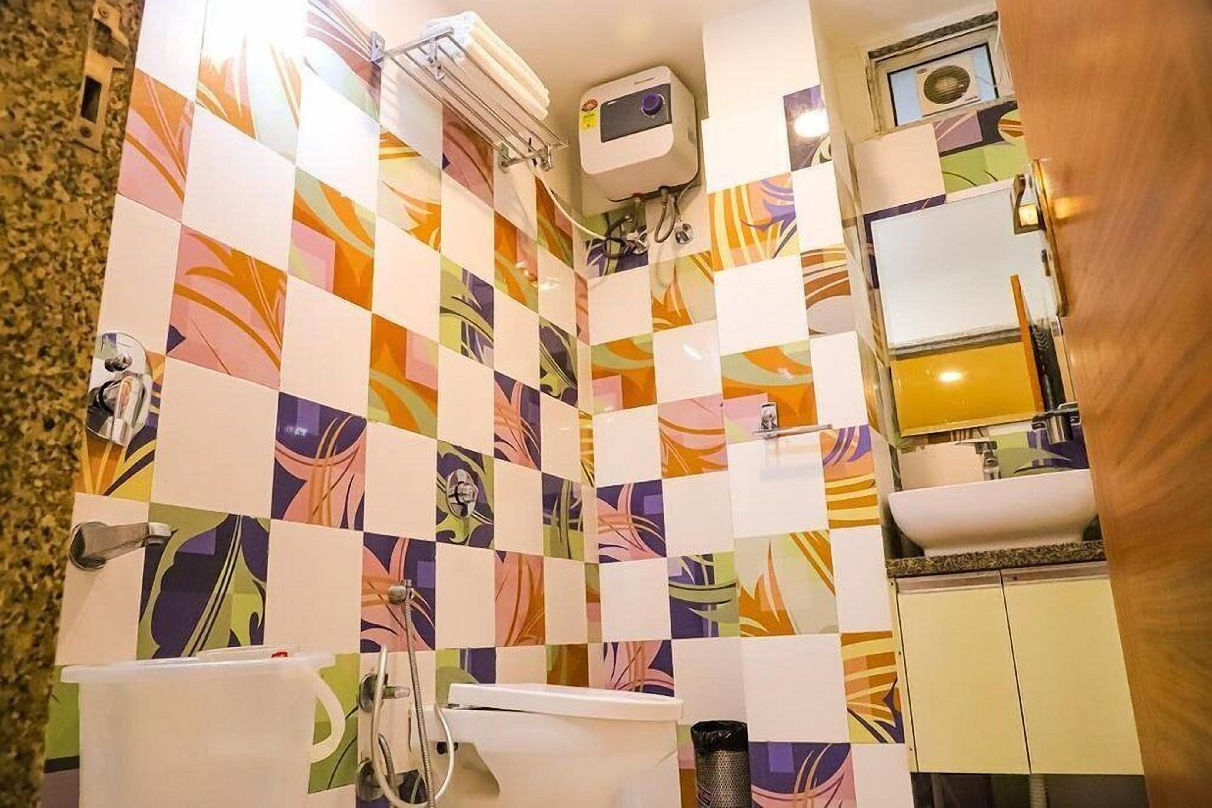A bathroom with colorful checkered tiles, a toilet, a sink, and a mirror.