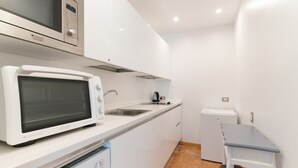 Een kleine keuken met een magnetron, broodrooster, spoelbak en een compacte koelkast.