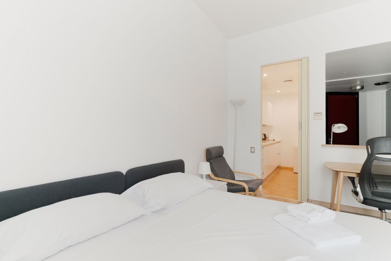 Une chambre d’hôtel avec un lit, une chaise, un bureau et un miroir.