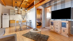 A modern kitchen with white appliances, a dining area with bar stools, a TV on a wooden cabinet, and a cozy living space with a fireplace. - Chabela's Penthouse Apartment with Sea Views, Jacuzzi, and Air Conditioning (La Lajita)