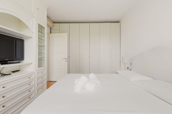 A bedroom with a bed, a TV on a dresser, and a wardrobe.