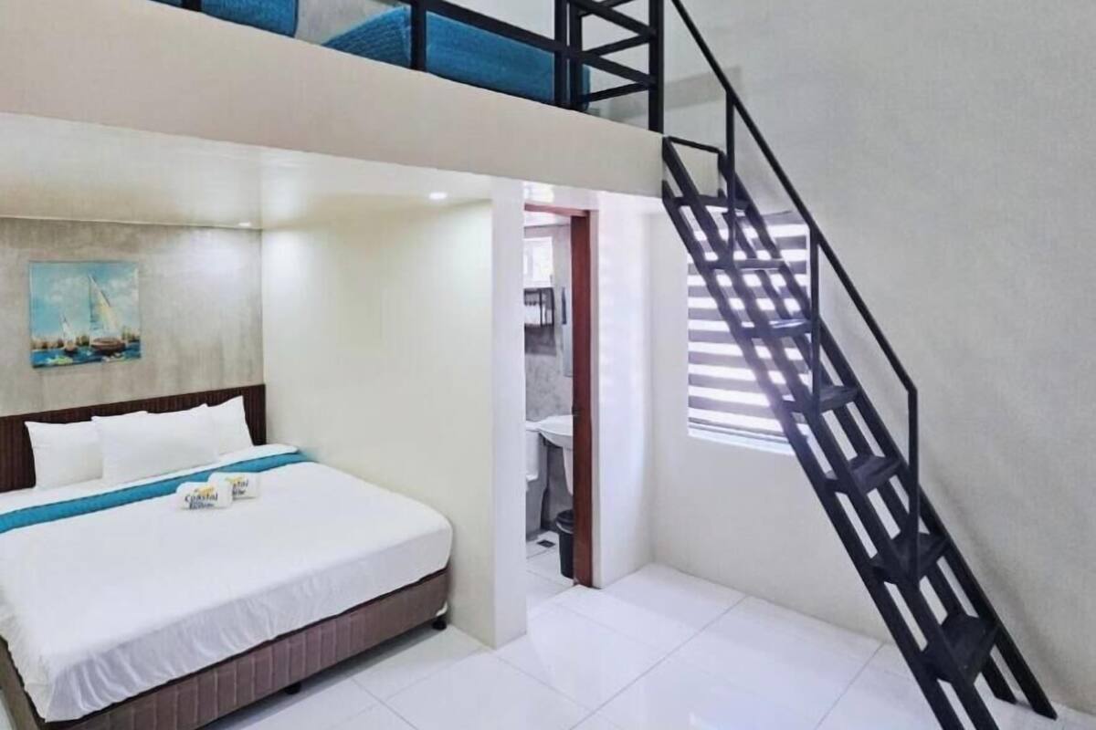 A bedroom with a bed, a painting, a staircase, and a view of the outside.
