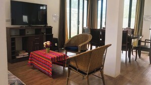A living room with a TV, a dining table with chairs, and a sofa.