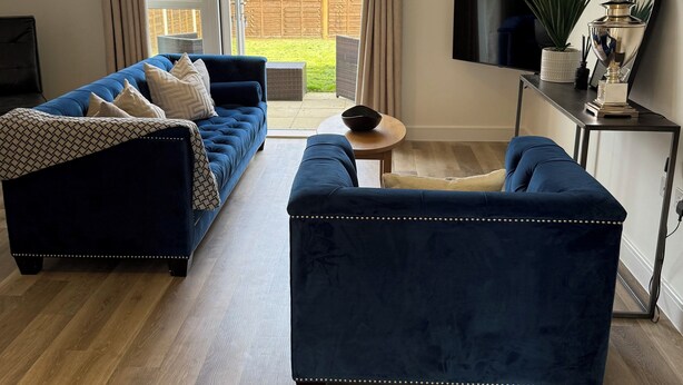 Un salon avec un canapé bleu, une table basse et un téléviseur posé sur un meuble.