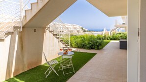 Une terrasse avec une table et des chaises, un escalier et une vue sur la mer.
