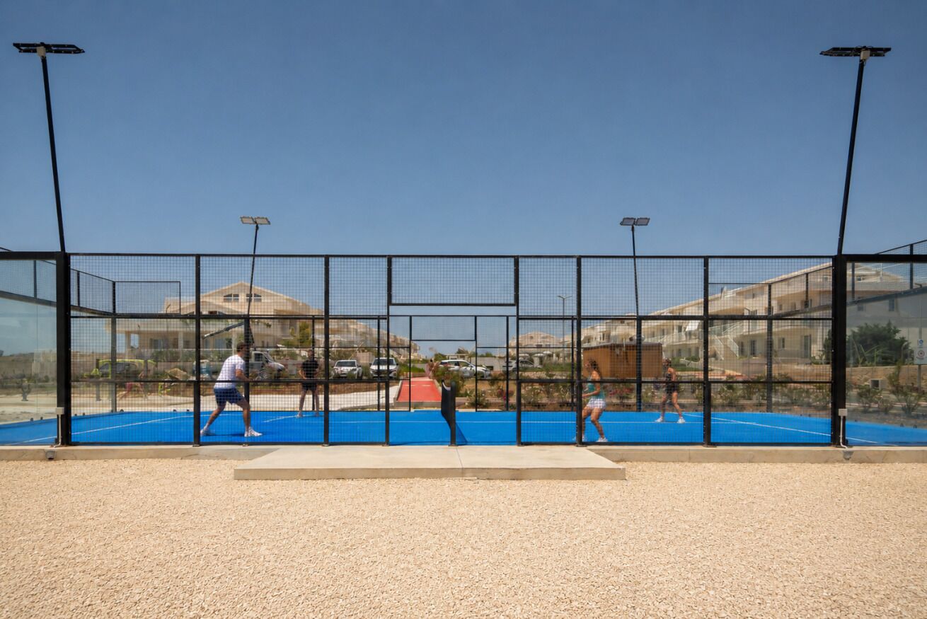 A tennis court with a net, surrounded by a fence, and solar lights.