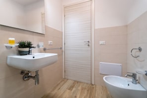Ein Badezimmer mit zwei Waschbecken, einem Spiegel, einer Pflanze und einer Tür.