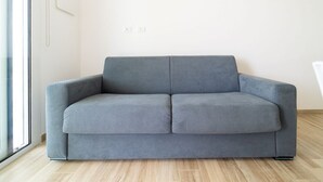 Een grijze bank in een kamer met een houten vloer en een witte muur.