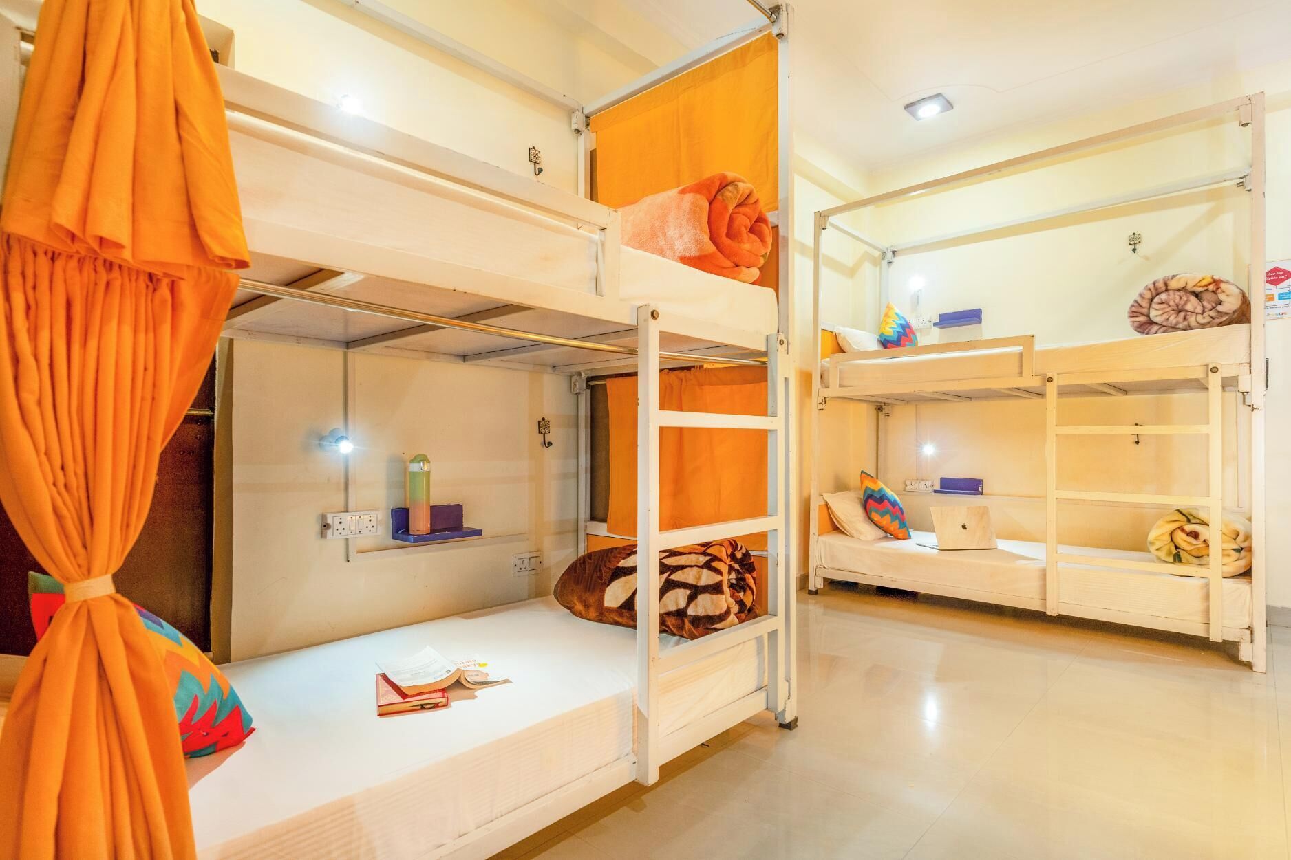 A bunk bed room with a ladder, shelves, and a small desk with a laptop.