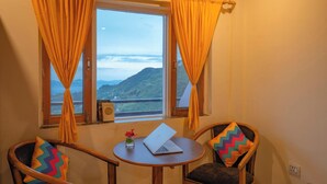 A room with two chairs, a small table, and a window with curtains. - goSTOPS Mussoorie Library Road (Mussoorie)