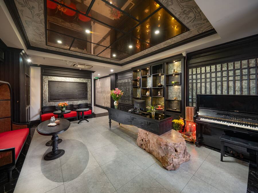 Amplia sala de estar con un piano, asientos y un detalle decorativo en la pared.