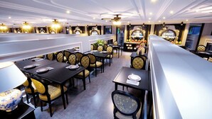 Un restaurant doté de nombreuses tables et chaises, de ventilateurs de plafond et d’un éclairage décoratif.