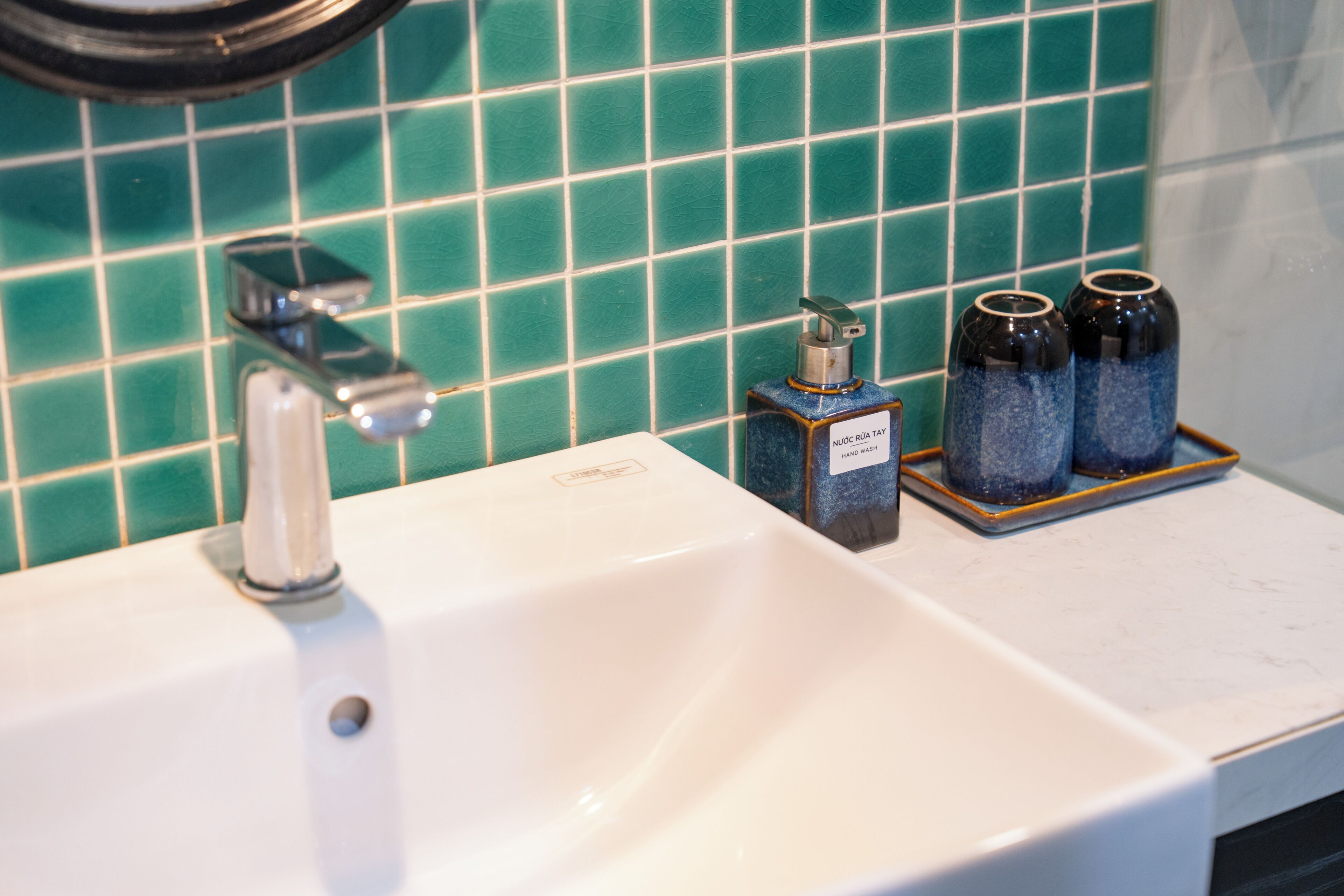 A bathroom sink with a faucet, a soap dispenser, and two bottles of hand soap on a tray.
