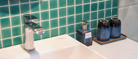 A bathroom sink with a faucet, a soap dispenser, and two bottles of hand soap on a tray.