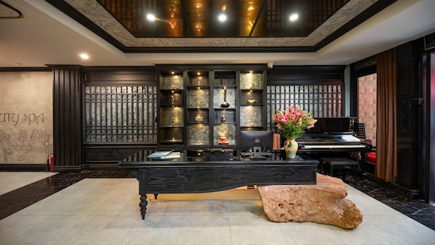 Un espace d’accueil avec un comptoir noir, un piano et un mur décoratif agrémenté d’étagères.