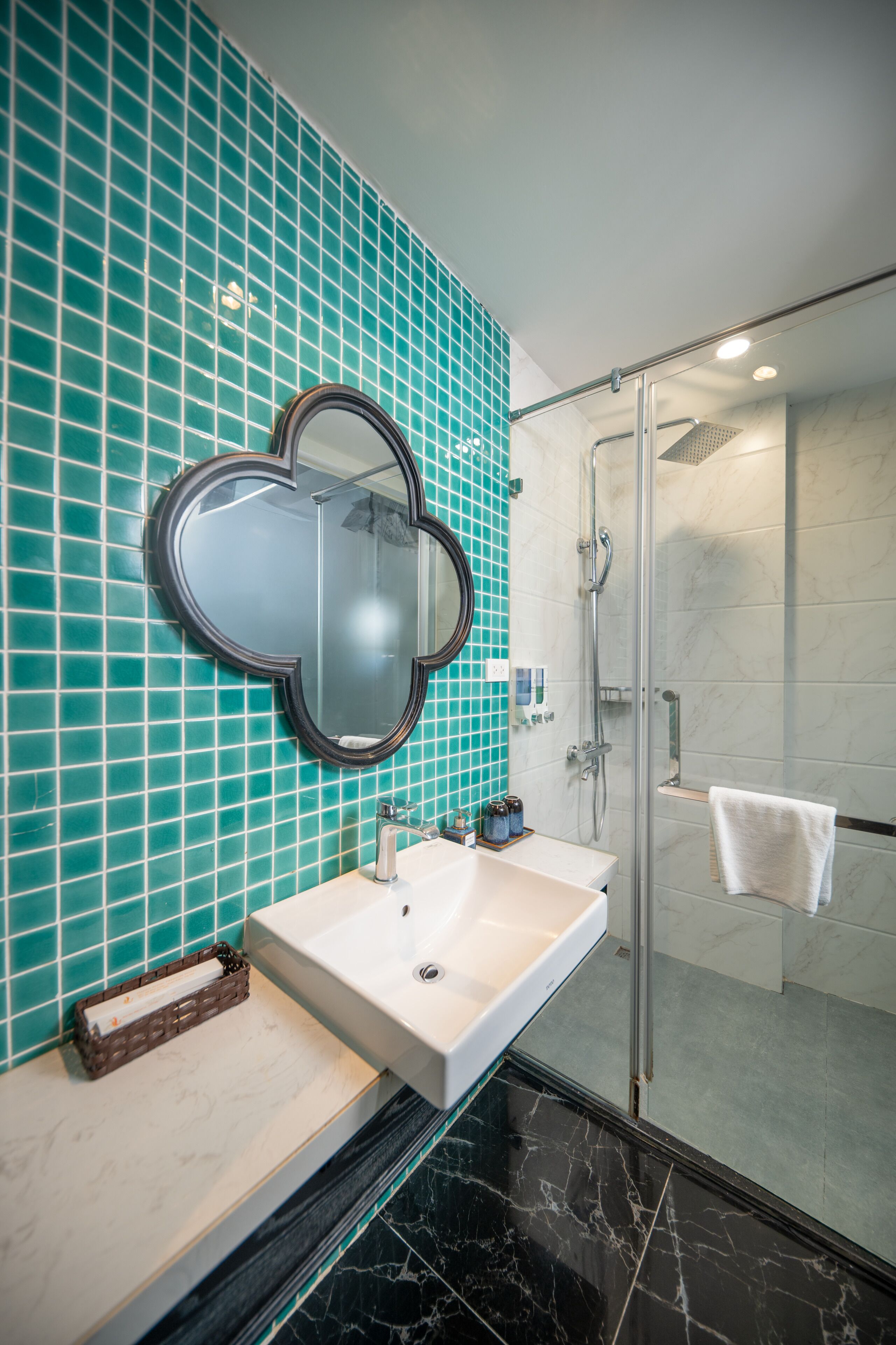 A bathroom with a large mirror, a sink, and a shower.