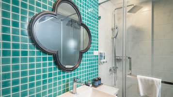A bathroom with a large mirror, a sink, and a shower.
