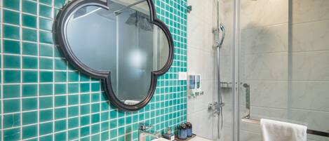 Un baño con un espejo grande, un lavamanos y una ducha.