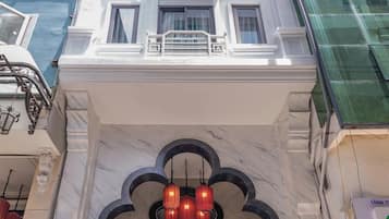 The entrance of the Royal Signature Hotel with a marble facade, a signboard, and traditional red lanterns.