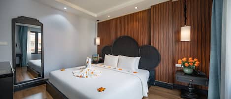 Habitación de hotel con una cama grande, panel de pared de madera y un espejo.