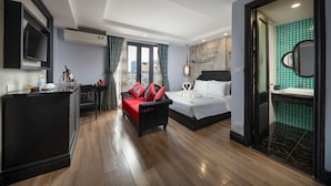 Une chambre d’hôtel comprenant un lit, un canapé, une télévision et une salle de bain avec un miroir et un lavabo.