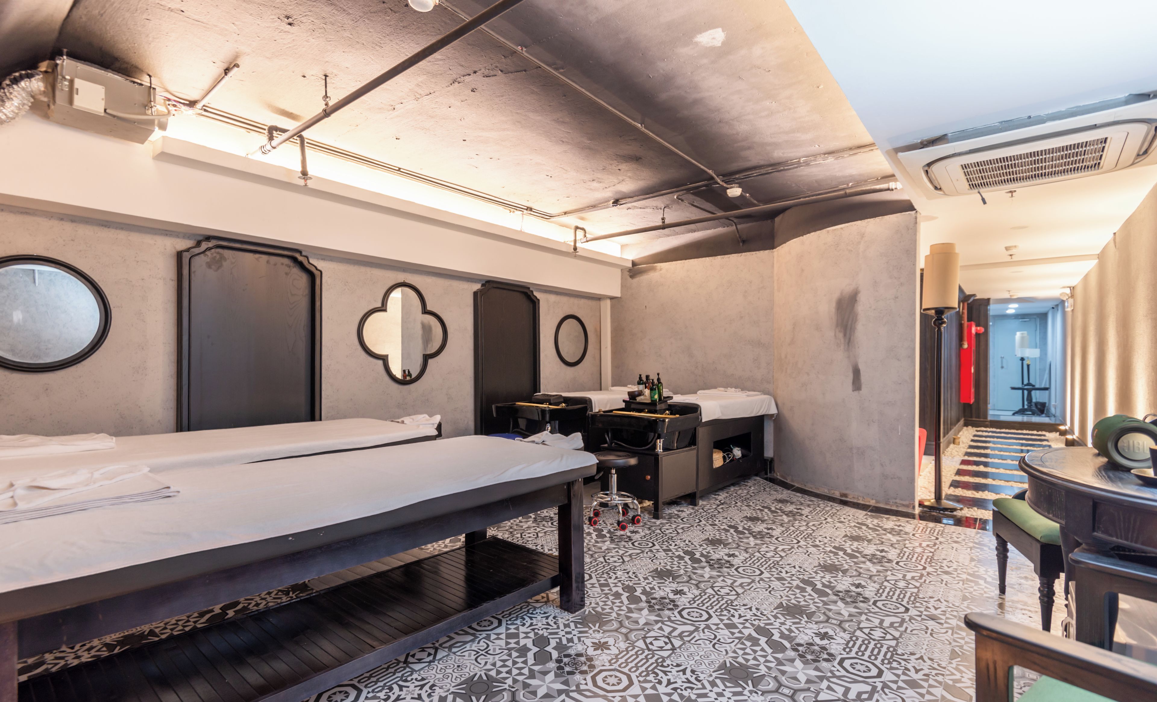 A room with bunk beds, a small table with a chair, and a patterned floor.