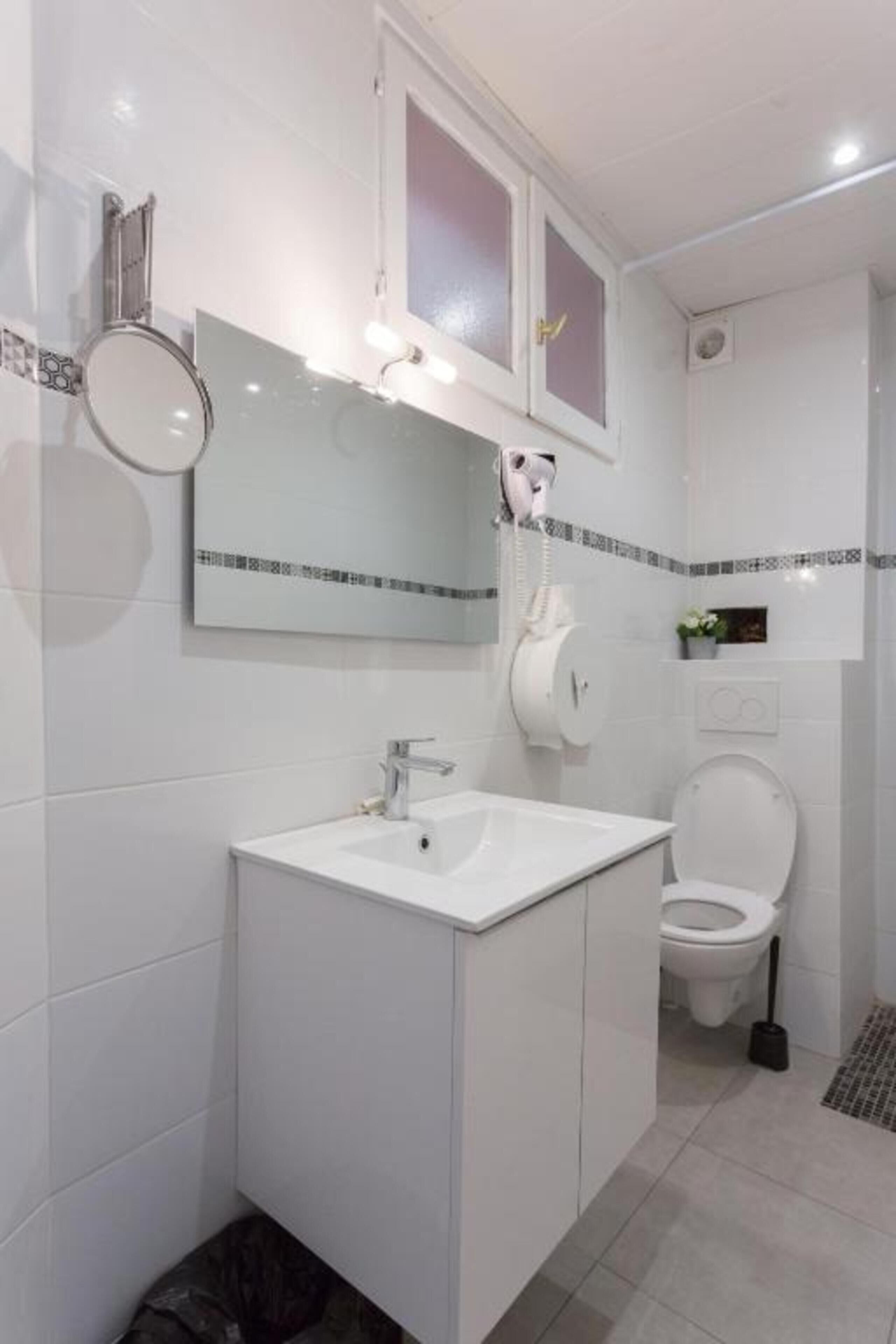 A modern bathroom with a white sink, mirror, and toilet.