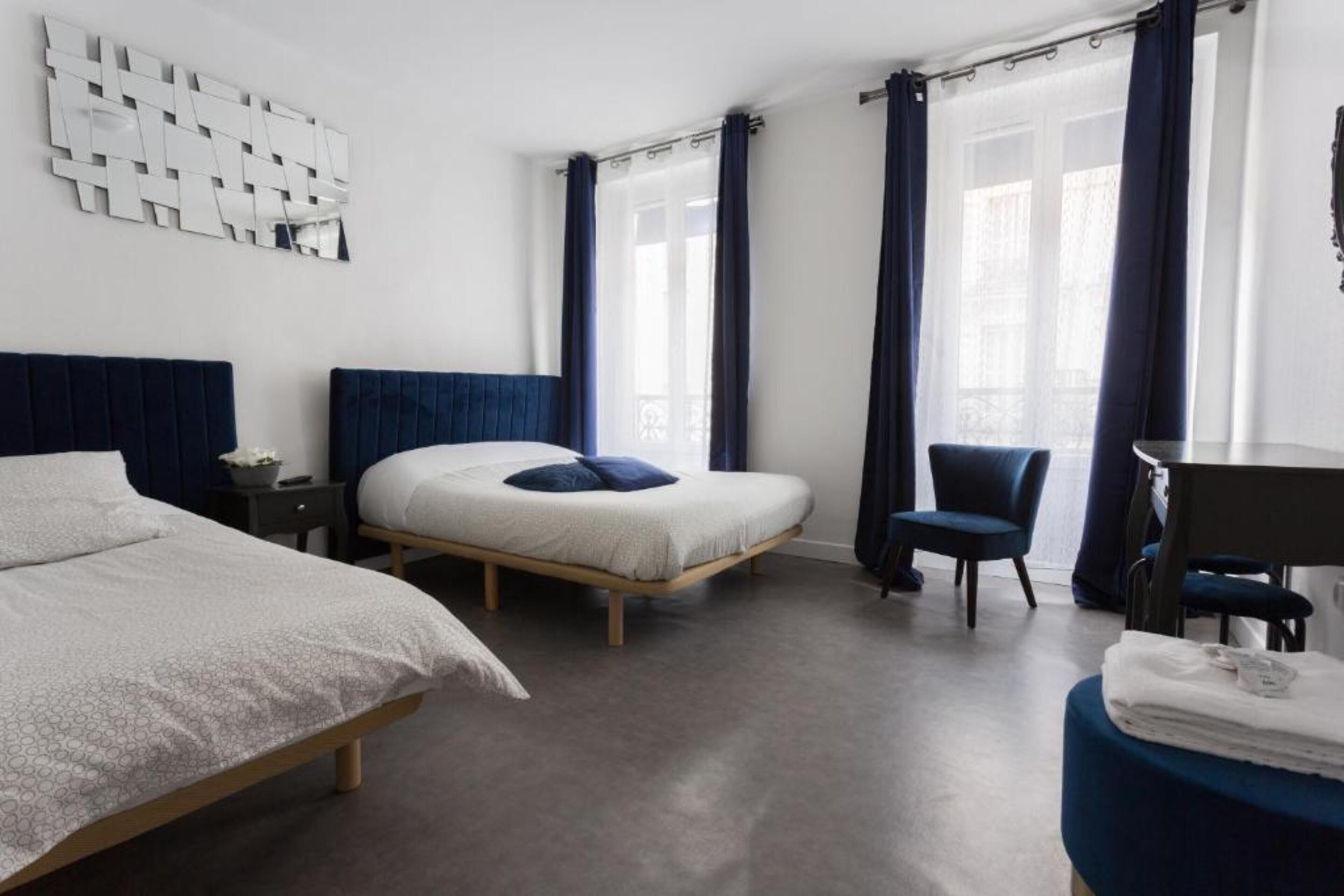Une chambre d’hôtel moderne équipée d’un grand lit, d’un lit plus petit, d’un bureau et d’une chaise.