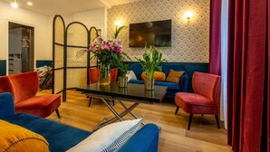 A modern living room with a sofa, chairs, a coffee table, and a TV mounted on the wall. - Europe BLV (Paris)