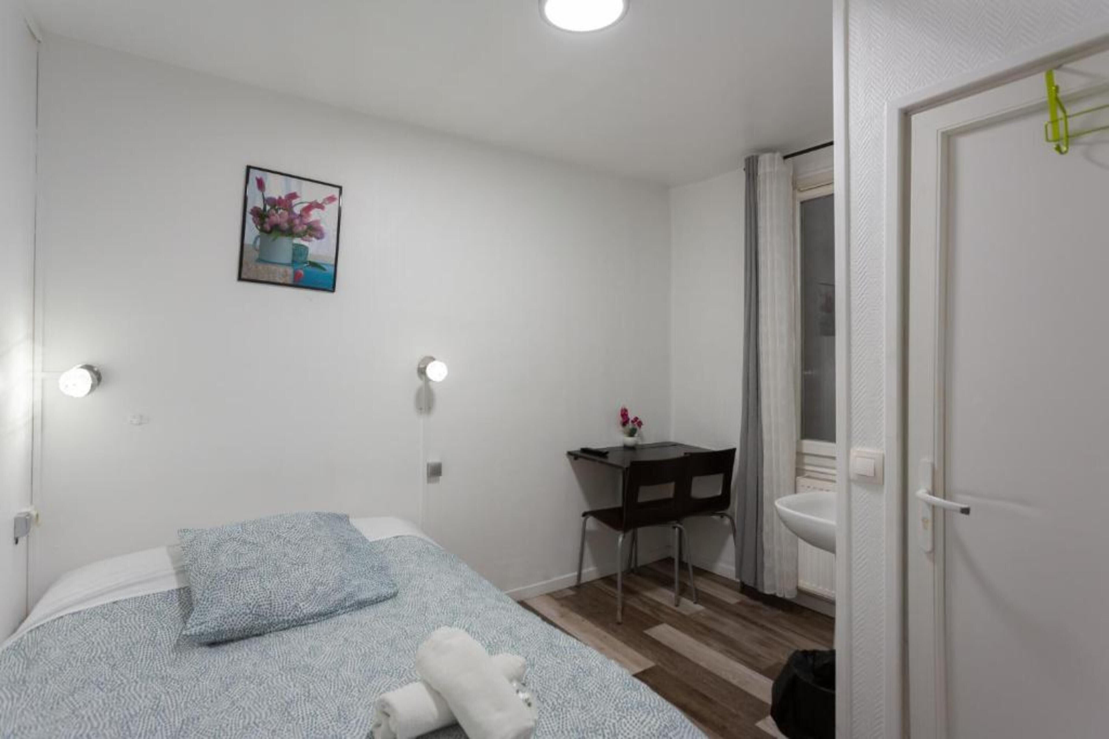 A small, clean room with a bed, a desk, and a bathroom.