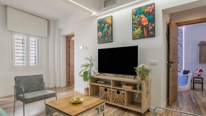 A modern living room with a flat-screen TV, a grey sofa, a wooden coffee table, and a TV stand with decorative items. - Apartment 'Casa Parque Benavente' with Private Terrace, Wi-Fi and Air Conditioning (Conil de la Frontera)