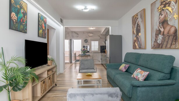 A modern living room with a flat-screen TV, a green sofa, and a dining area in the background. - Apartment 'Casa Parque Benavente' with Private Terrace, Wi-Fi and Air Conditioning (Conil de la Frontera)