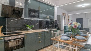 A modern kitchen with a built-in oven, microwave, and a dining area with a table set for four. - Apartment 'Casa Parque Benavente' with Private Terrace, Wi-Fi and Air Conditioning (Conil de la Frontera)