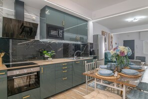 Una cocina moderna con horno empotrado, microondas y comedor con una mesa preparada para cuatro.