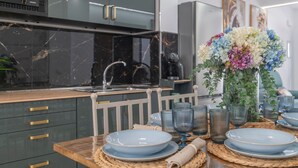 A modern kitchen with dark cabinetry, a marble backsplash, and a dining area with blue plates and glassware. - Apartment 'Casa Parque Benavente' with Private Terrace, Wi-Fi and Air Conditioning (Conil de la Frontera)