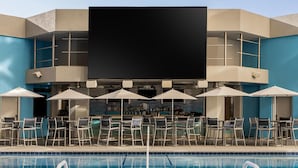 Ein Barbereich am Pool mit Sitzgelegenheiten im Freien und einem großen Bildschirm.