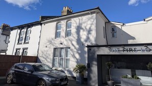 A white building with a garage labeled "THE AIRS LO" and a parked car. - OYO Firs Lodge London Heathrow| Standard Double (Hounslow)