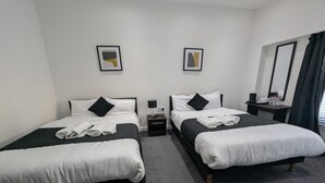 Una habitación de hotel con dos camas individuales, una mesita con una lámpara y un espejo en la pared.