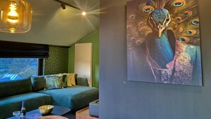 A modern room with a green sofa, a wooden coffee table, and a peacock painting on the wall.