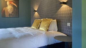 A bedroom with a bed, a painting, and two wall-mounted lights.