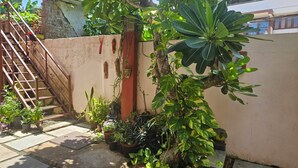 Un petit espace jardin agrémenté de plantes en pot, d’un escalier en métal et d’un mur orné d’éléments décoratifs.
