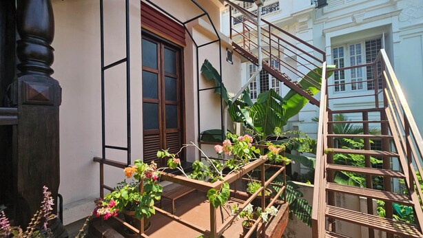 Un escalier avec une rampe en métal menant à un balcon agrémenté de plantes et de fleurs en pot.