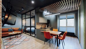 Un espace de vie moderne comprenant un canapé, une table à manger et des chaises, un coin cuisine et de grandes fenêtres.