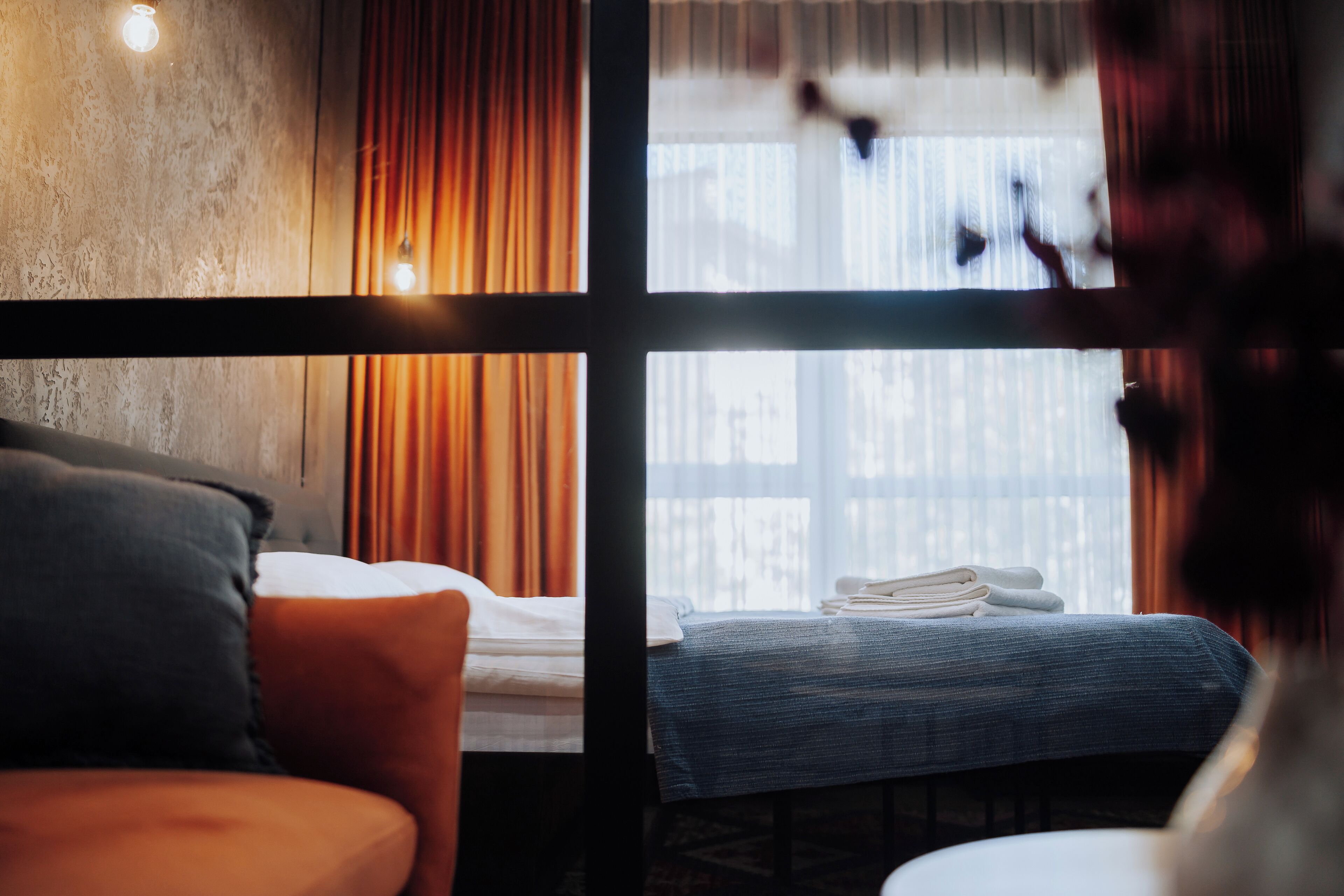 A hotel room with a bed, a window with curtains, and a view of the outside.