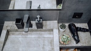 Une salle de bain dotée d’un lavabo, d’un robinet et d’un miroir au design moderne.